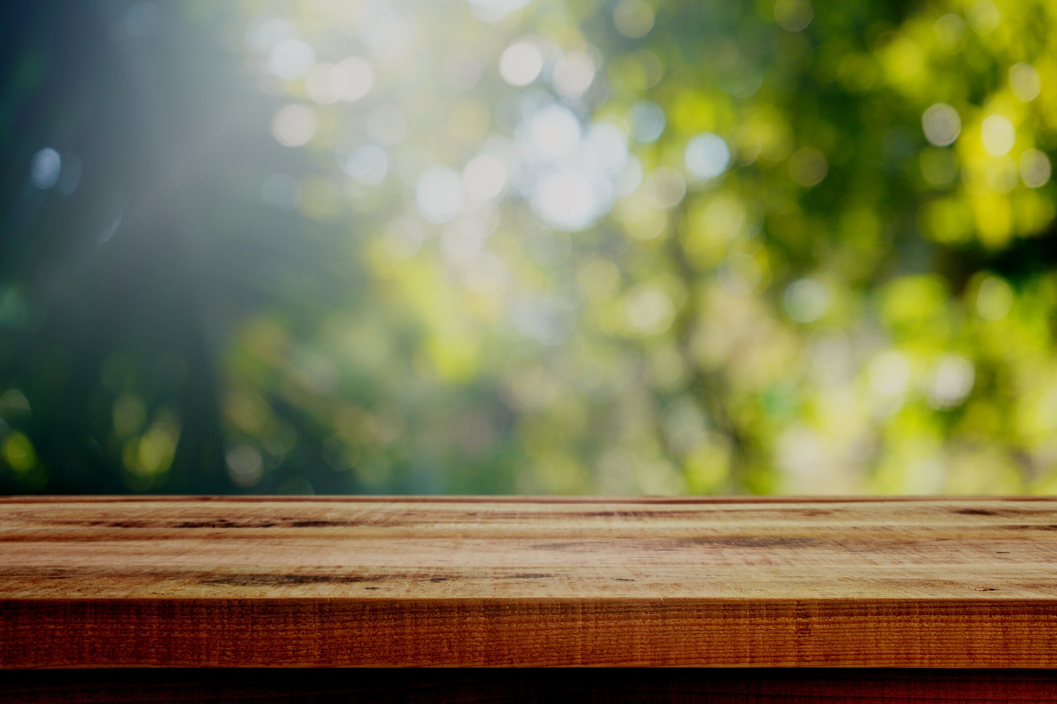 Wooden table and blurred green nature bokeh background for product.